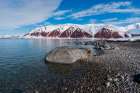 A gravel shoreline and snow covered mountains border Bockfjorden-Spitsbergen Island-Norway Art Print